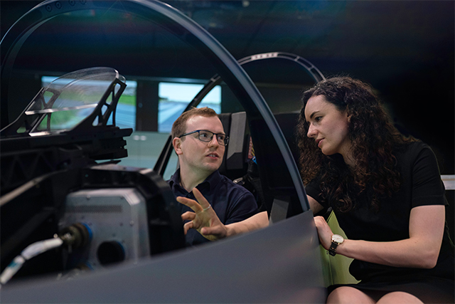 a woman in the space industry instructing a male counterpart in the lab