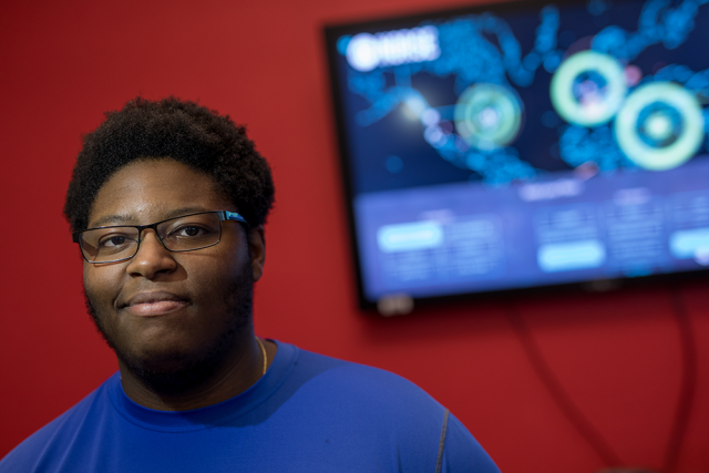 portrait of Joshua Joseph, cybersecurity student, in front of a monitor