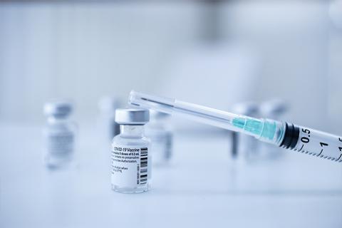 a syringe sitting on top of a covid 19 vaccine vial symbolizes the increased cybersecurity threats for healthcare industry