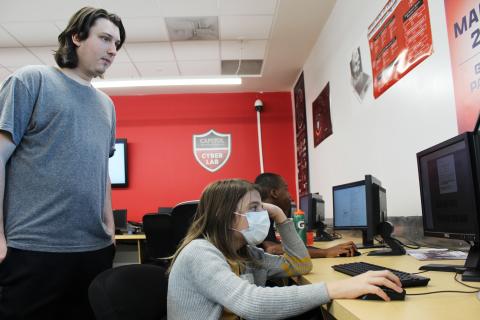 student looking over shoulder of child on computer