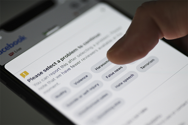 close up of a phone screen showing a community guideline reporting form exemplifies how the has internet impacted terrorism