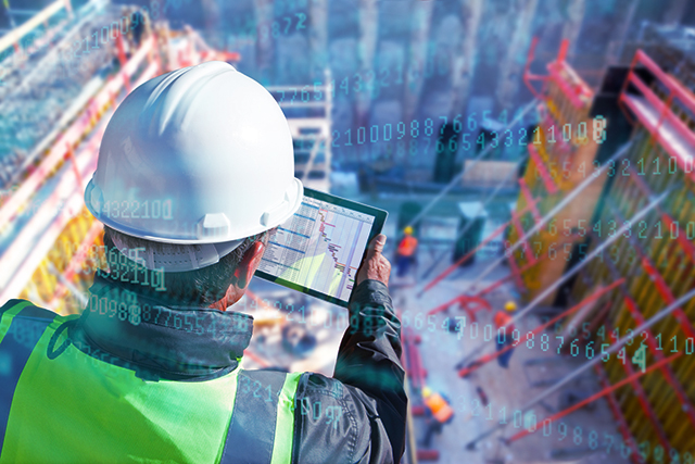 a man in a hard hat looking down on a construction site with a laptop using cloud and mobile technology in construction