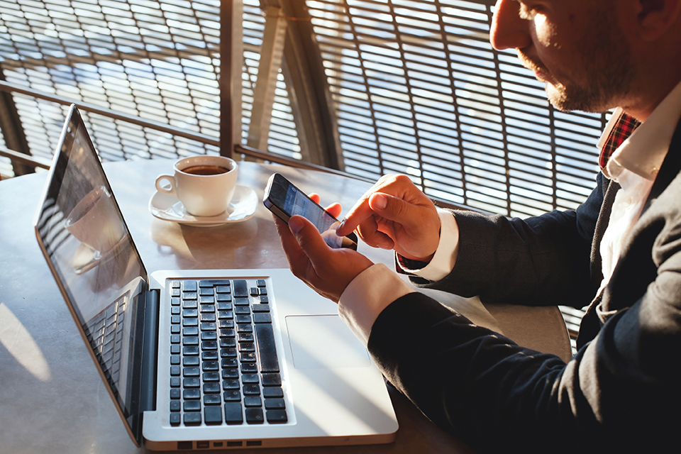 Stock photo of a businessman using a phone and laptop