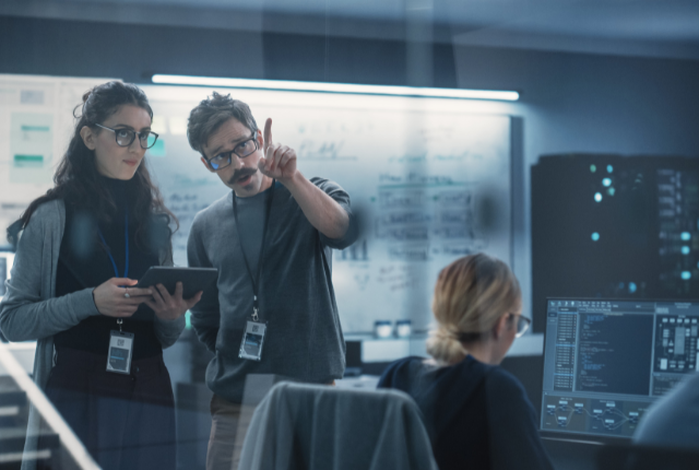 two information security workers in office with computer monitors 