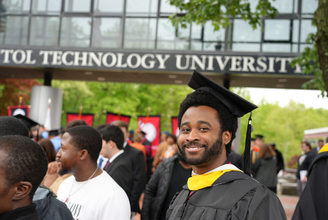 2023 Capitol Tech Graduate Smiling under Sign