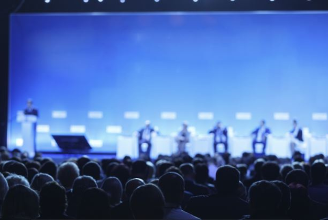 People attending a conference, looking at stage