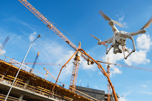 a drone is seen in front of a construction site with cranes as an example of construction safety management trends