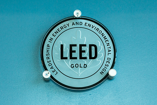 a LEED certification plaque hangs on a teal wall awarded for green building and construction management