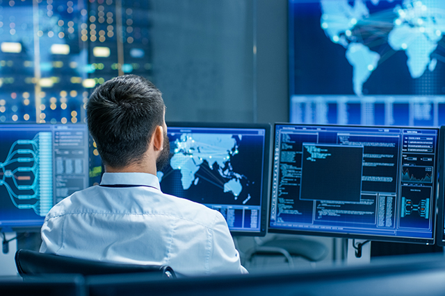 a person who has built a career in counterterrorism looks at a computer screen with maps and software