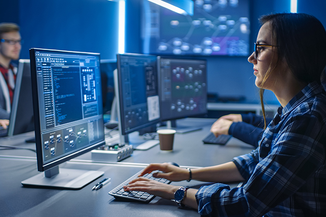 a woman works on a desktop in cybersecurity to symbolize how a computer science degree helps with cybersecurity