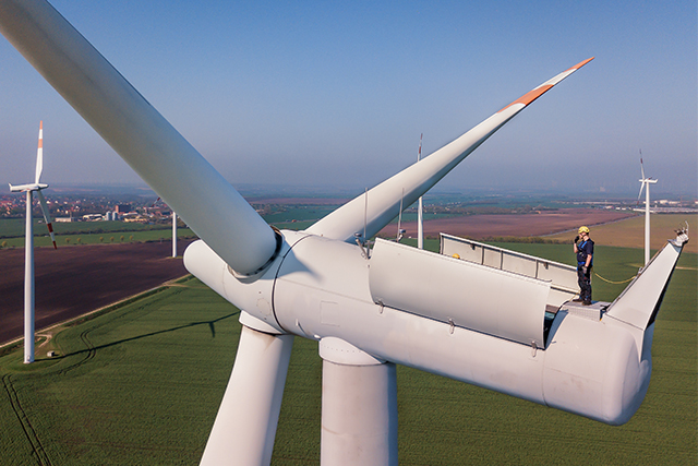 a man in a hard hat working in mechatronics engineering and renewable energy systems fixes a wind turbine