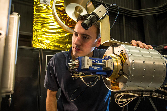 a man with a mechatronics engineering career in aerospace stands next to a mechatronics device