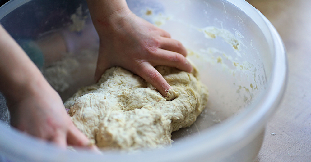 Photo of a pizza maker kneading the dough