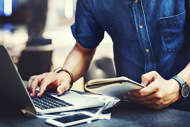 a man in a denim button down on a laptop pursues a career with top paying employers for mechatronics engineers