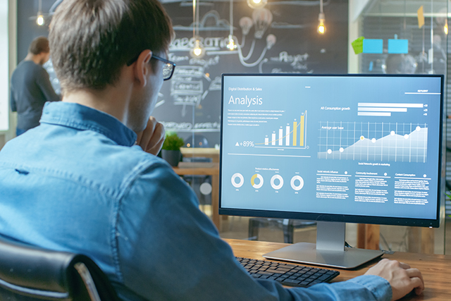  a man works on a data analysis on his desktop to symbolize what cyber analytics students should know about mitre attack