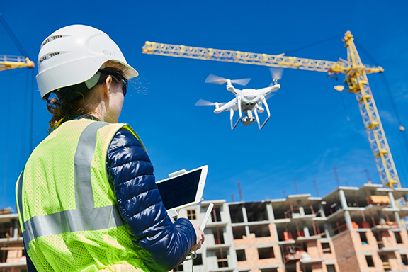 construction worker operating drone at construction site during national safety month