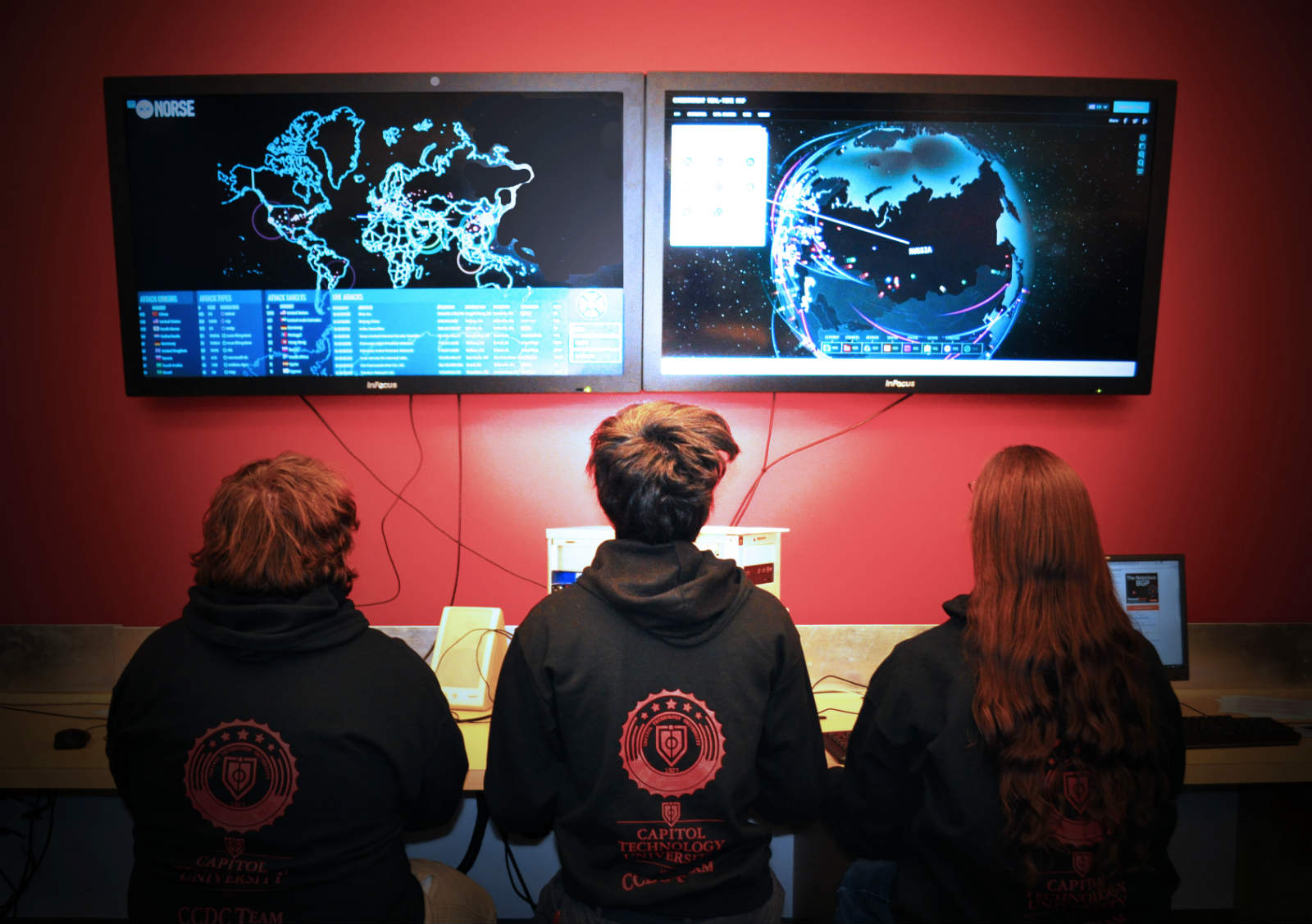 three students looking at screens in Cyber Lab testing critical infrastructure