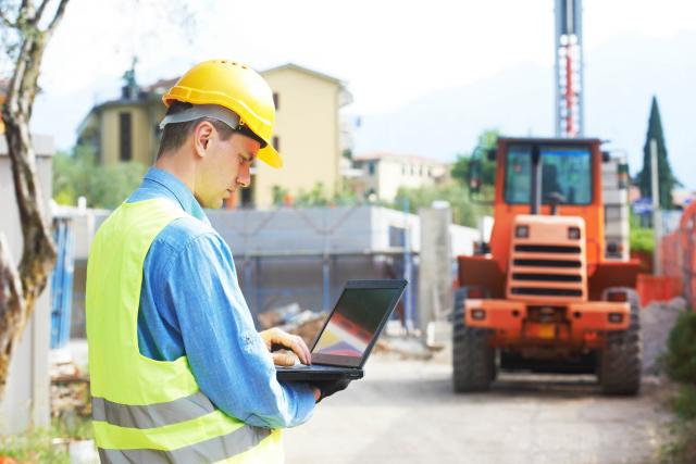  construction manager on laptop at construction site signifies how cybersecurity can affect construction