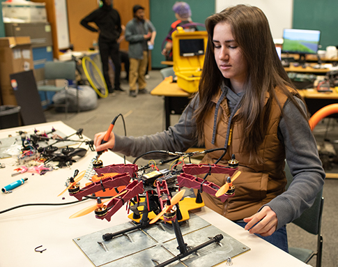 Female student using engineering tools to work on drone