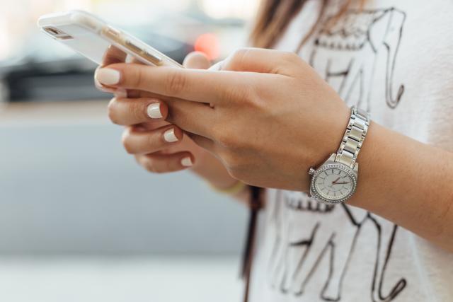 a close up of a woman's hands using her cellphone demonstrates the need for managing consumer privacy with cybersecurity regulations