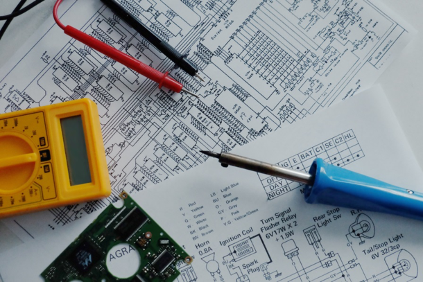 electrical testing tool laying over mechanical engineering drawings showing how it's different from mechatronics