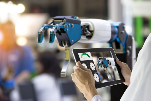 hands holding tablet taking image of mechatronics arm showing how it's different from mechanical engineering