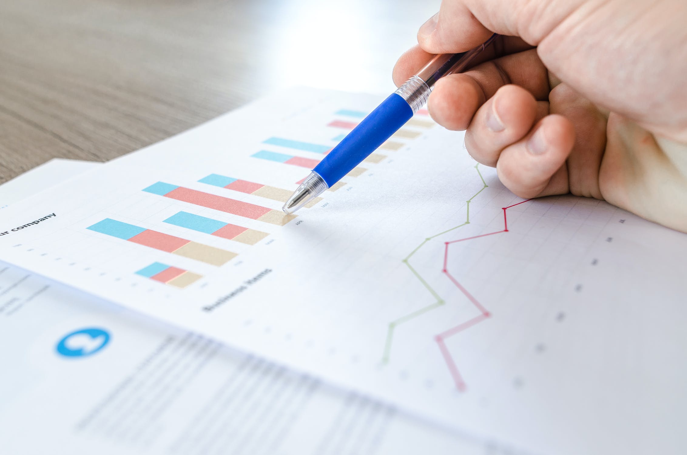 Person analyzing data on a sheet of paper with a pen