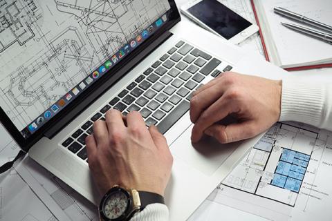 a man works on space planning in facilities management with a schematic showing on his laptop screen