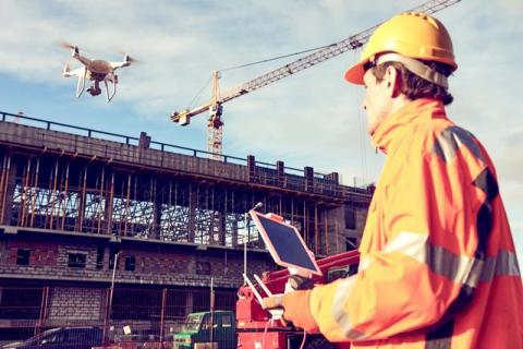 worker flies drone on construction site