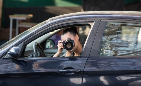 Stock photo of a woman in a car pointing a camera