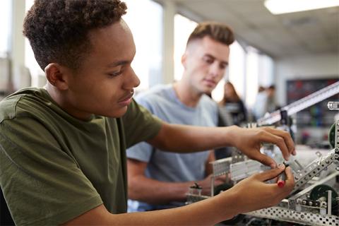 Two students consider mechatronics engineering while working building a robot in the classroom