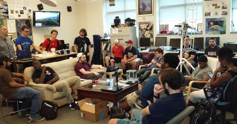 large group of students talk in lab