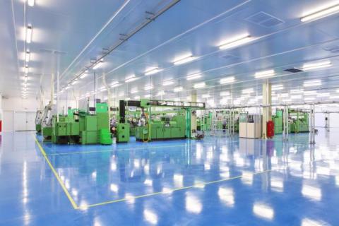 a well-lit facility with green machinery exemplifies the importance of lighting in facilities for worker safety and productivity